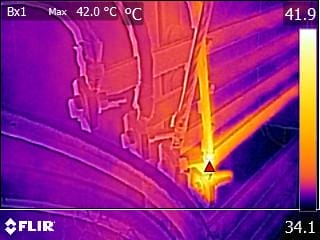 Thermal image from a thermography inspection of mechanical equipment shows heat distribution; a bright yellow area marks a hot spot (42.0°C) near a joint, with cooler regions in purple and blue tones.