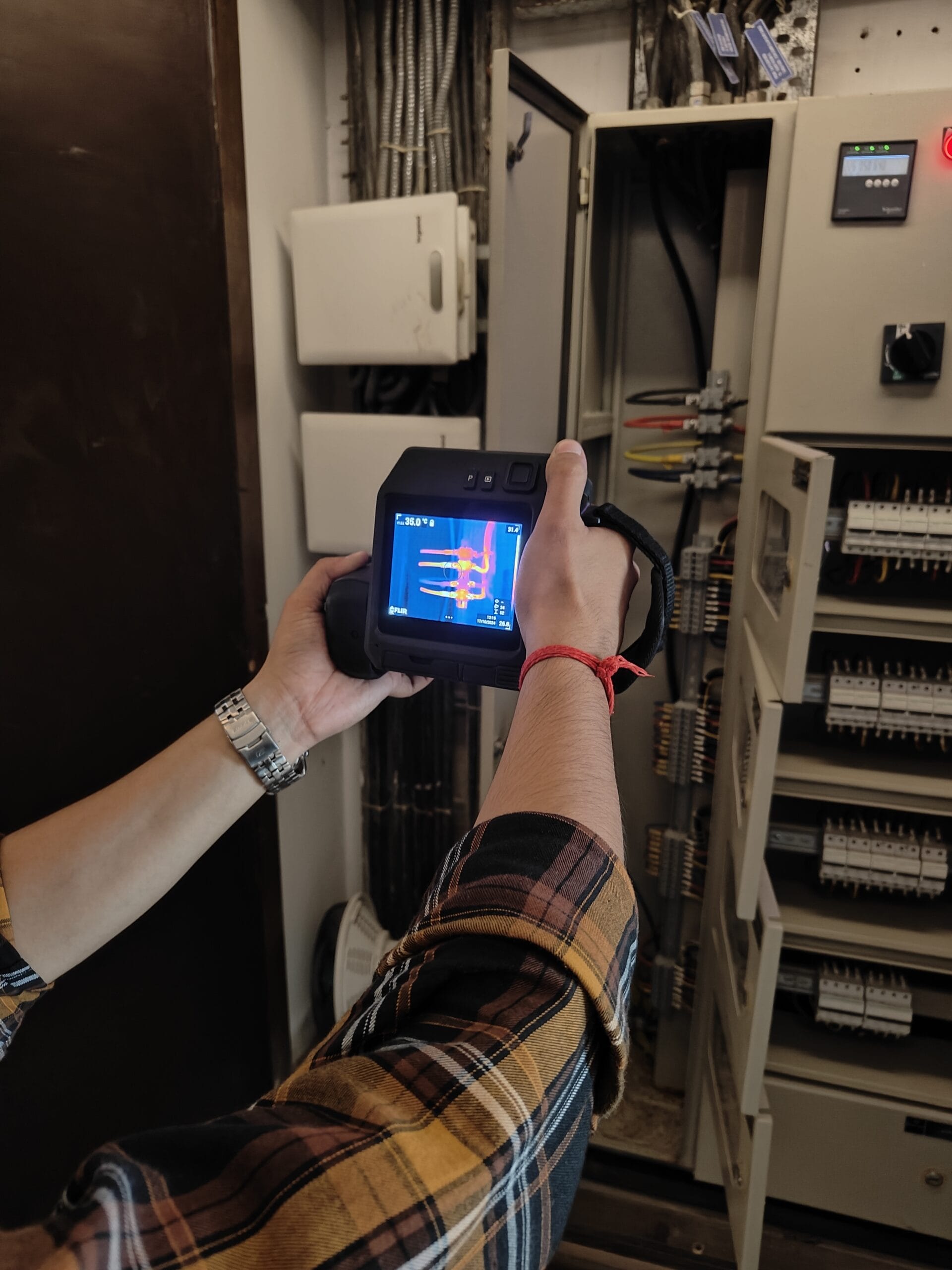 Engineer performing electrical panel thermography inspection using infrared thermal camera